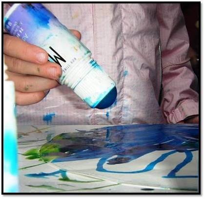 This may contain: a person is painting with blue and white paint on the table next to a bottle