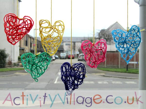 This may contain: several heart shaped paper clips hanging from the side of a street pole in front of houses