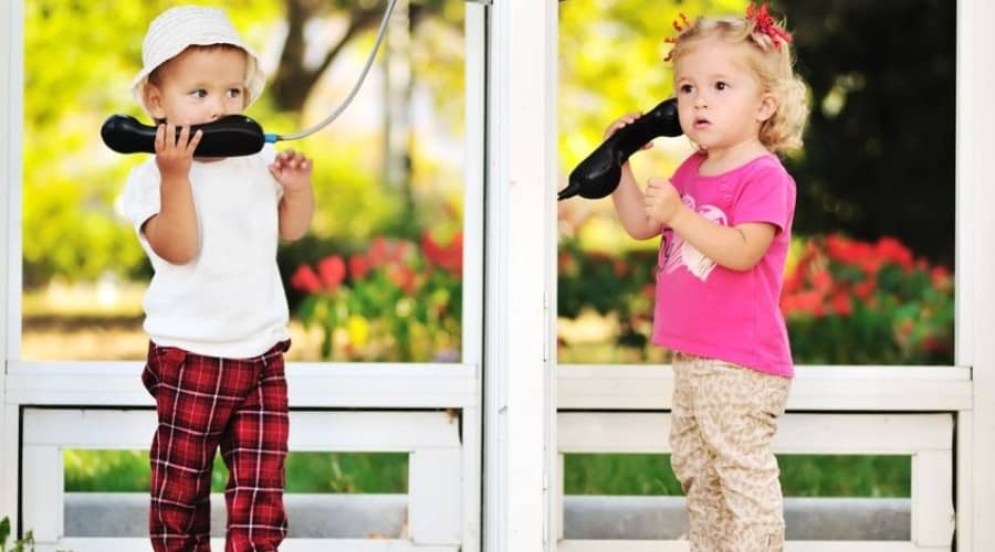language activities for preschooler-language development-two young girls having a phone conversation outside