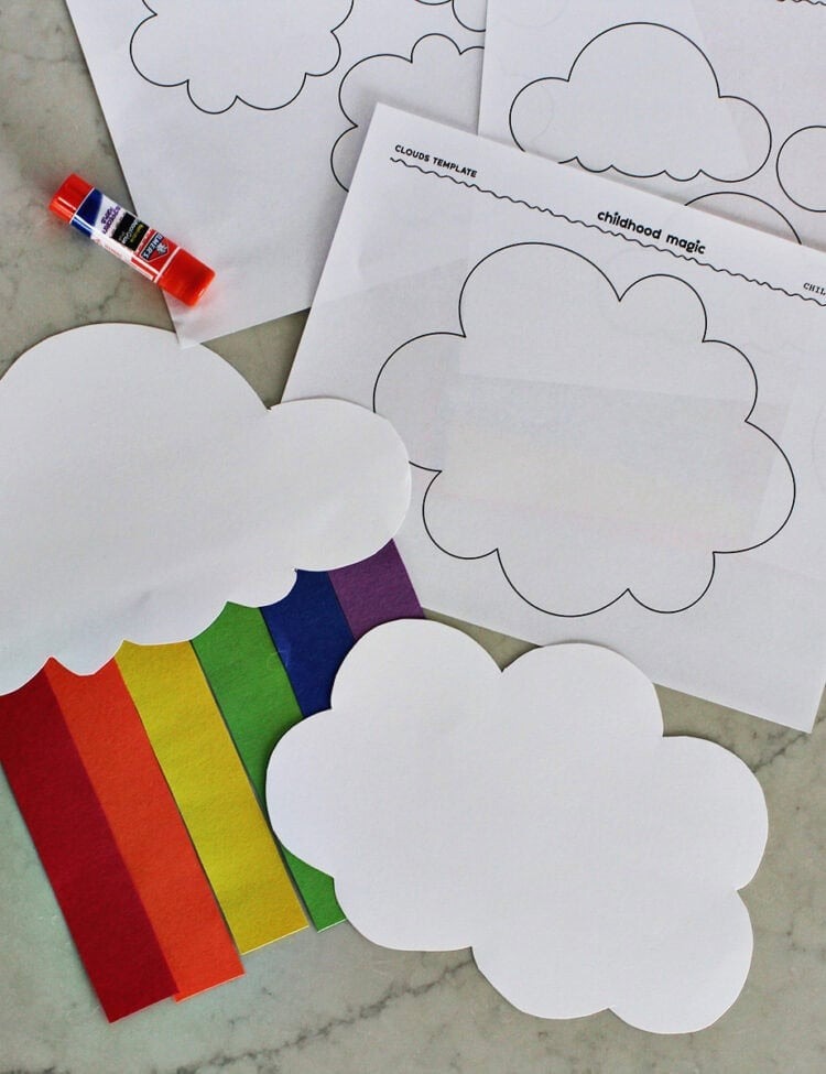 Cloud cutout with paper strips to make a rainbow next to printable pages of clouds by a gluestick.