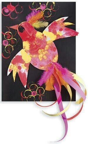 A child glues a petal shaped piece of blue paper to his eric carle inspired collage flower.