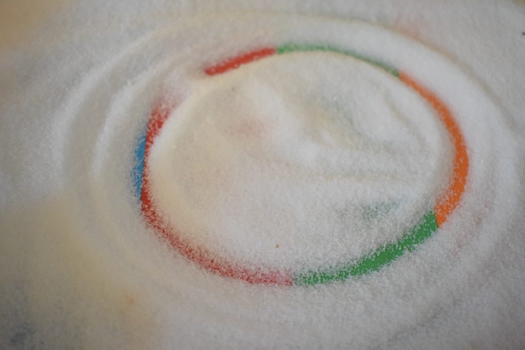 salt tray with circle drawn by toddler-showing the need to practice multisensory pre writing shapes
