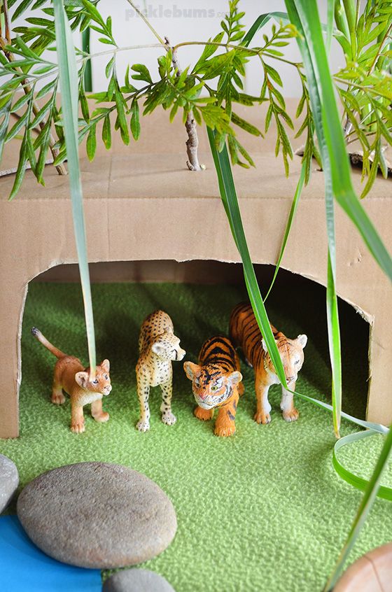 This may contain: there are many small toy animals on the ground in front of some plants and rocks