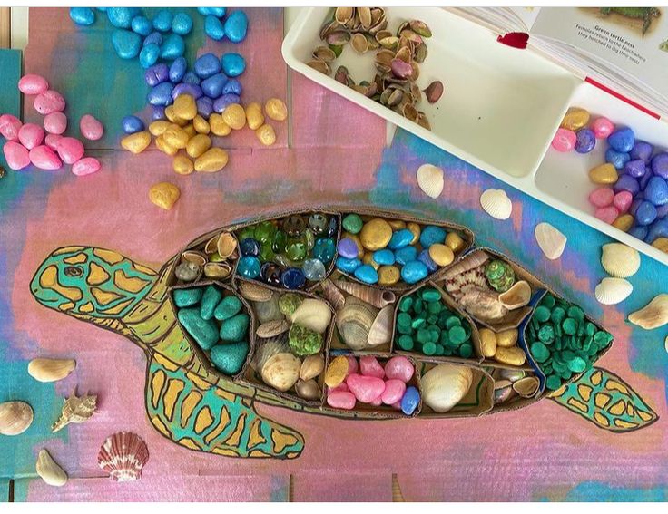 This may contain: a turtle made out of rocks and pebbles sitting on a table next to other items