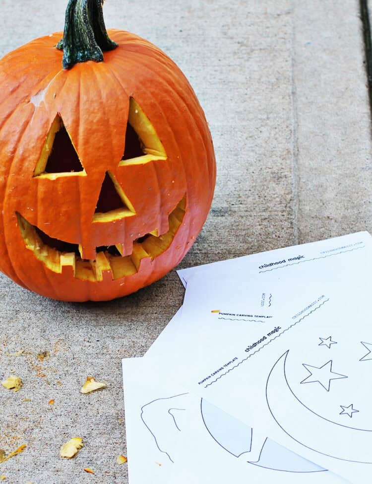carved pumpkin sitting next to pumpkin carving templates.